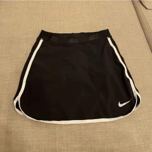 Nike Kjol ”tennis skirt” i svart. Det finns en ficka i den där man kan lägga saker. Under kjolen är det shorts under. 