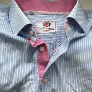 Blå skjorta  - En blå skjorta med smala vita ränder. Råkade köpa en för stor storlek. Den ska skitta lite ”oversized” i stilen men den är ändå lite för stor. Den är nästan helt oanvänd 