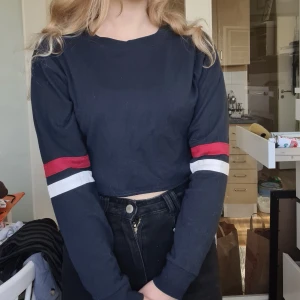Långärmad crop top - Långärmad crop top i mörkblå färg och detaljer på ärmarna. Fint skick och en väldigt snygg tröja. 