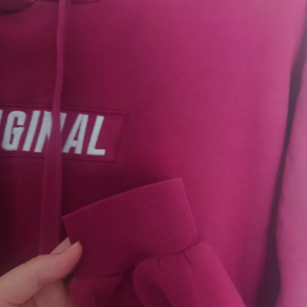 Vinröd hoodie med text på. Står att det är storlek 