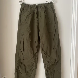 Parachute pants - Gröna parachute/cargo byxor, kan dras åt i midjan så passar S/M. Användes ett fåtal gången.