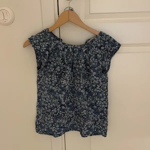 Topp - Blå blommig topp från Hm med knapp som stängning i nacken.