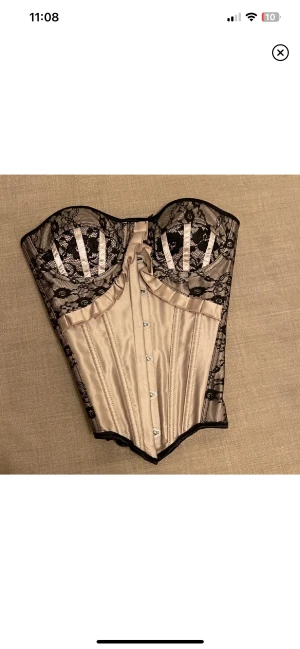 Korsett  - Korsett i beige silke med svarta spets detaljer. Skicka dm om ni vill ha bild på hur det sitter. 