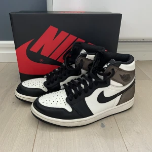 Air Jordan 1 Retro High Dark Mocha - Hej! Säljer nu mina Jordans 1 mocha. Använt i lite mindre än ett år. Köpte dessa för runt 5000kr. Har tyvärr inte kvar kvitto men äkthetsbevis finns. Og box. Dem har ett litet skrapmärken på höger tå som syns på bilden. Skriv för fler frågor. 