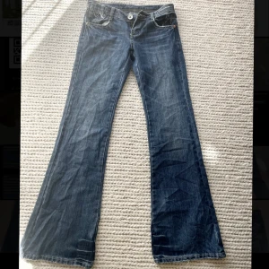 Lågmidjade jeans  - Längd: 100 cm  Innerbenslängd: 81 cm  Midjemått: 78 cm  Jeansen är tyvärr för små på mig som har storlek S vanligtvis. Passar bra för XS eller XSS. I byxorna står det att det är storlek 25, vilket inte säger mig något. Buda!