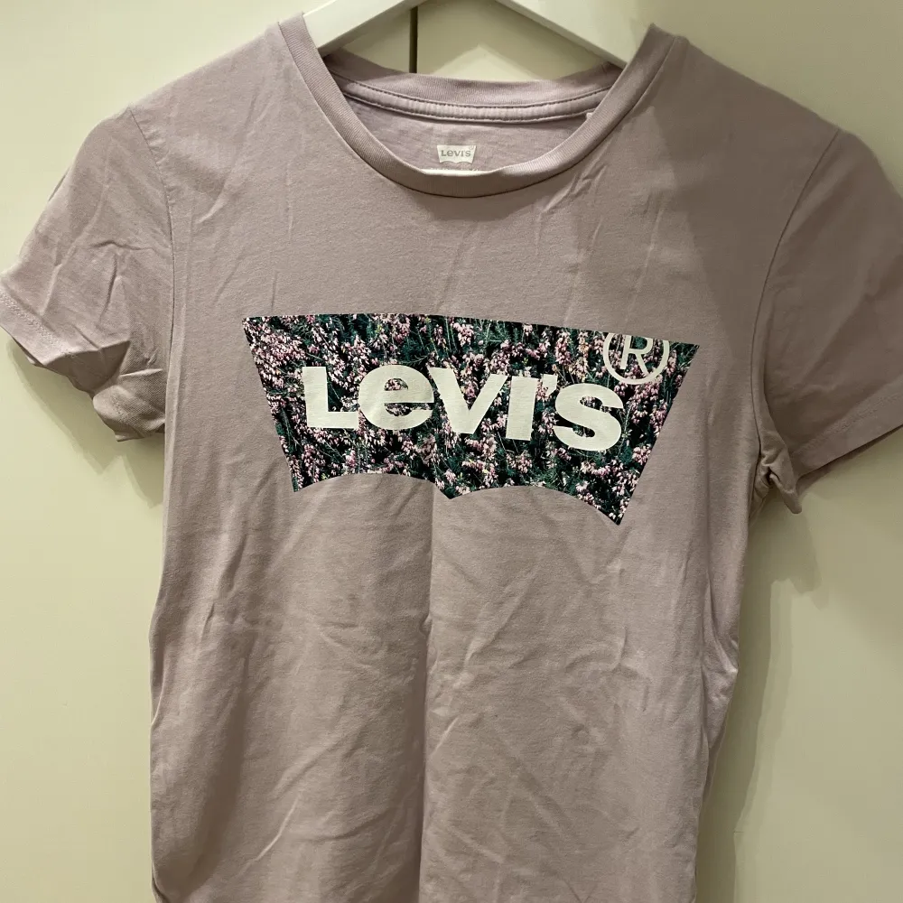 Blommig levi’s t-shirt i 100% bomull. Färgen är ljuslila. Fint skick.. T-shirts.