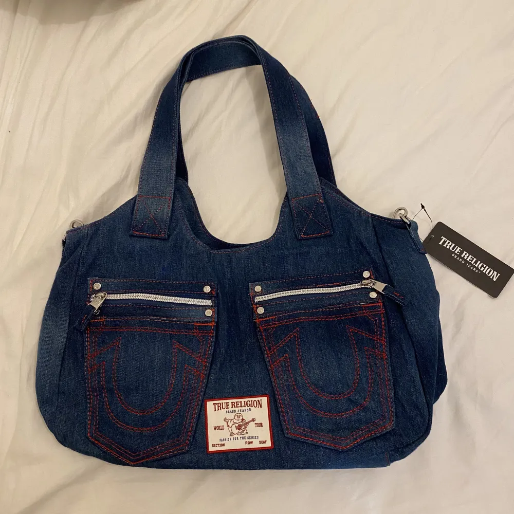 Supersnygg och cool väska från True Religion. Väskan är i jeanstyg, och är helt oanvänd med lappen kvar! Säljs pga att jag har en likadan i en annan färg! Köptes för cirka 1080kr i USA💓 (jag samfraktar!!). Väskor.