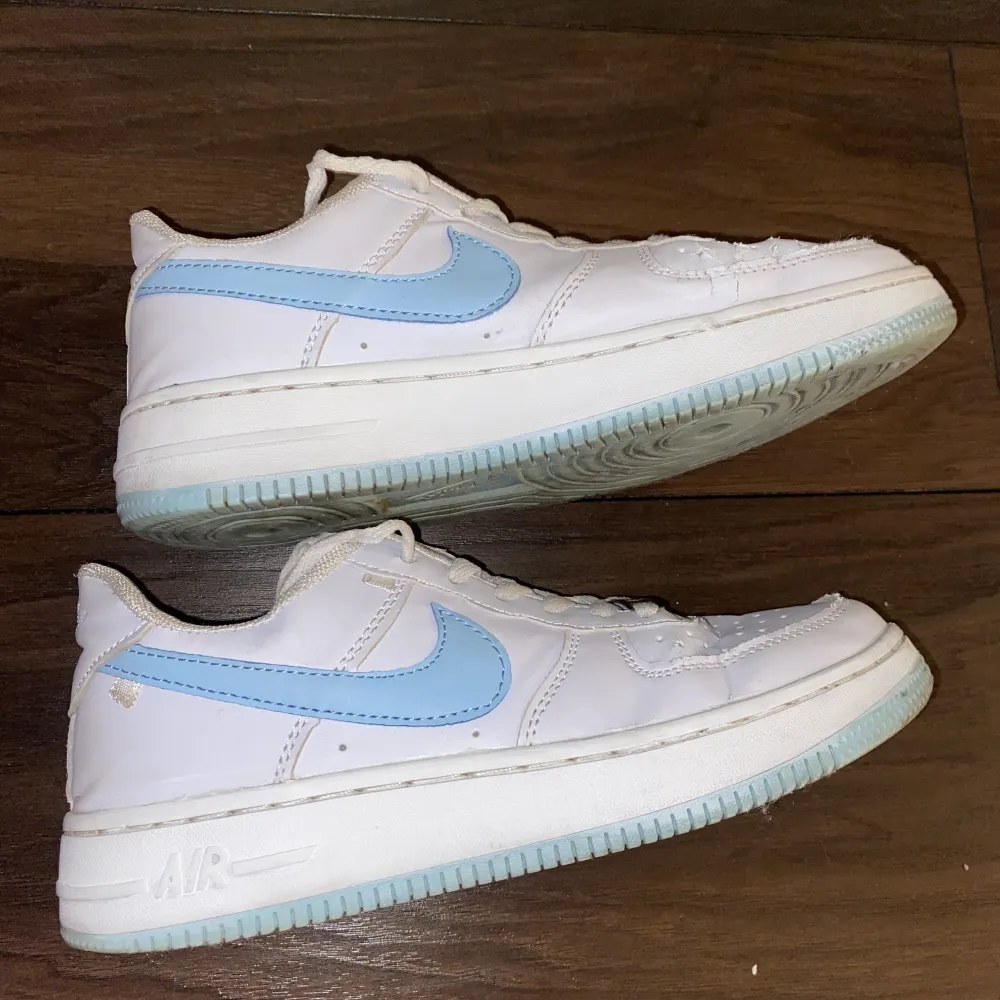 Vita Nike air force 1 med ljusblå logga och sula. Använda men i bra skick! Storlek 39. Skor.