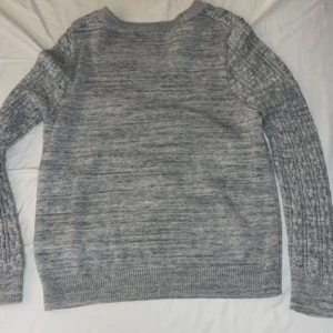 Stickad tröja  - En grå långärmad stickad tröja som är för liten för mig, inga skavanker. Den är i strl XL men är definitivt för stor i storleken. Skulle säga att den är mer som XS-S