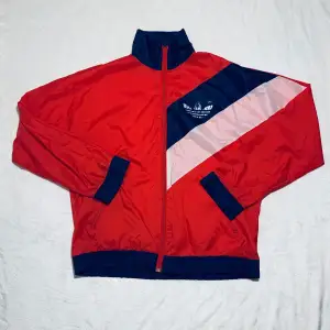 Vintage 90s Adidas vindjacka. En tunn vind jacka från tidigt 90tal som är i mycket bra skick bortsett från att trycket med loggan är lite nött. Passar S/M