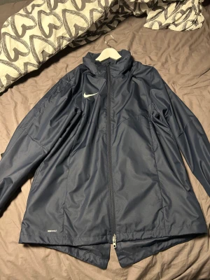 Nike javka - Helt ny vindjacka från Nike. Säljer pga för stor. Sitter som L/XL. Luvan sitter i jackan. Nypris 800kr Hör av dig vid intresse eller fler frågor😊