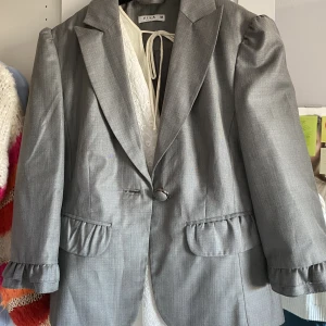 Jacka  - Söt medellång- ärmad ”kavaj” med volang på ärmarna från Vila. Storlek s 