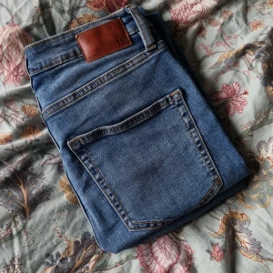 Blå högmidjade jeans - Högmidjade jeans med hål på knäna. Använda fåtal gånger.  Stretchigt material storlek M Från lager 157 märke SKY