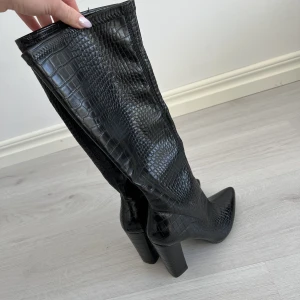 Stövlar från Nelly - Helt oanvända stövlar från NLY Shoes. Klackhöjd är 9,5cm och går till strax under knät. I strl 38.