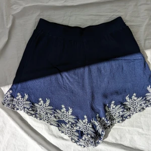 Broderade shorts - Mörkblå broderade shorts i flowy viskos, lite plisserade i tyget. Hög midja.