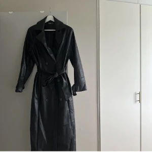 Skinn trenchcoat - nyskick - Aldrig använd skinnimitation trenchcoat. Är i storlek 38, mycket efterfrågad! Köpte den för 799kr, säljer den för endast 249kr. Priset kan diskuteras!