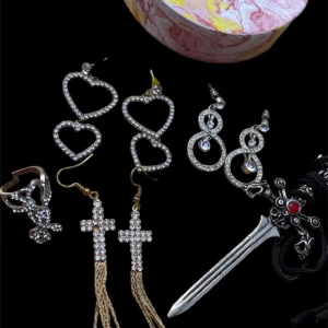 Smycken - Smycken 35kr/st förutom svärdet som är 50kr. Säljer även den rosa grejen som är gjord av porslin, 40kr. (Hjärtörhängen sålda) Ju mer man köper ju billigare blir det. En av kors örhängena saknar en rhinestone.