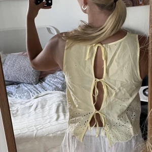 Gul topp - Gul somrig topp med vita broderade detaljer och knytning i ryggen. Köpt 2nd hand, nyskick💛