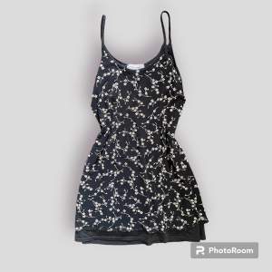 Jättefin kort klänning som har två lager, ett svart och ett med ett blommigt mönster i mesh. 