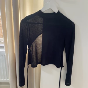 Svart topp med öppen rygg.  - Svart topp med öppen rygg. Knyte vid ryggen. Genomskinlig!  Hög vid halsen. Använd fåtal gånger. 