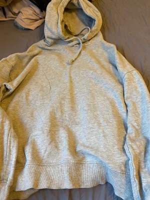 Grå Hoodie - Grå hoodie i storlek M. Den har som ett sträk på fram sidan som inte går bort.