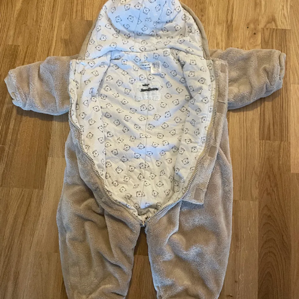 Teddy overall med öron Fint begagnat skick Märke: Cocoon  Ej vanlig storleksmärkning, bild 4 visar storlekslappen. Det står 71.  När jag lägger denna ovanpå en overall med storlek 68 så är denna något större så rimligtvis är denna något mellan 68-74.. Jackor.