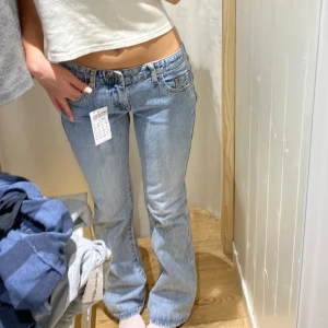 Lågmidjade jeans från Brandy Melville  - Lågmidjade jeans i modellen Elinore från brandy melville. I fint skick, slitage längst ner på dem dock. Färgen skulle jag säga är mest sann på tredje bilden. Jag är 170 som referens.  Från hemsidan- Measurements: 22cm rise, 77cm inseam, 74cm waist