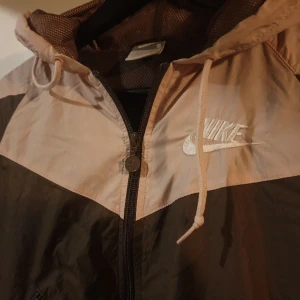 Nike - Träningsjacka / vindjacka från Nike. I brunt och ljurrosa. Snygg och himla skön på med sitt nät-aktiga foder (vadmannukallardet? Berätta gärna om Du vet! <3)).   Storlek S, men jag upplever att den ev är mer som XS.  Gott skick :) 