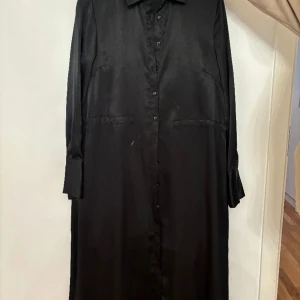 Svart klänning  - En lång svart klänning med bälte. Ordpris 599kr