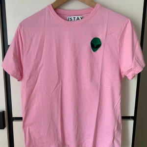 Rosa T-shirt - Denna T-shirt har aldrig använts.  Obs. Plagget kommer att tvättas innan det skickas iväg.