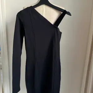 Superfin svart långärmad one shoulder klänning från Stylein.