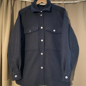 Marinblå jacka - En fin jacka i marinblå från ellos i storlek 38/40 köpte den för ny pris 599kr. Den är i fint skick men är knottrig. !Köparen står för frakt!