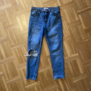Jeans - Blåa jeans m hål från Gina Tricot i storlek 38. Använda men i fint skick. Ganska stretchiga. Passar mig som har midja ca 75 och stuss ca 98. 