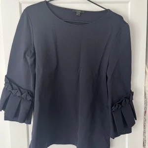 Topp från cos  - Mörkblå topp från cos med volang ärmar. Går att både klä upp och ner!🥰Väldigt härligt och exklusivt material!