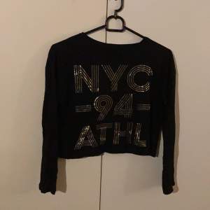 Säljer denna snygga svarta tröjan med guld ”NYC” text, då den blivit för liten. Använd fåtal gånger och är i bra skick! Det står ingen storlek på tröjan men den är som en xxs-xs