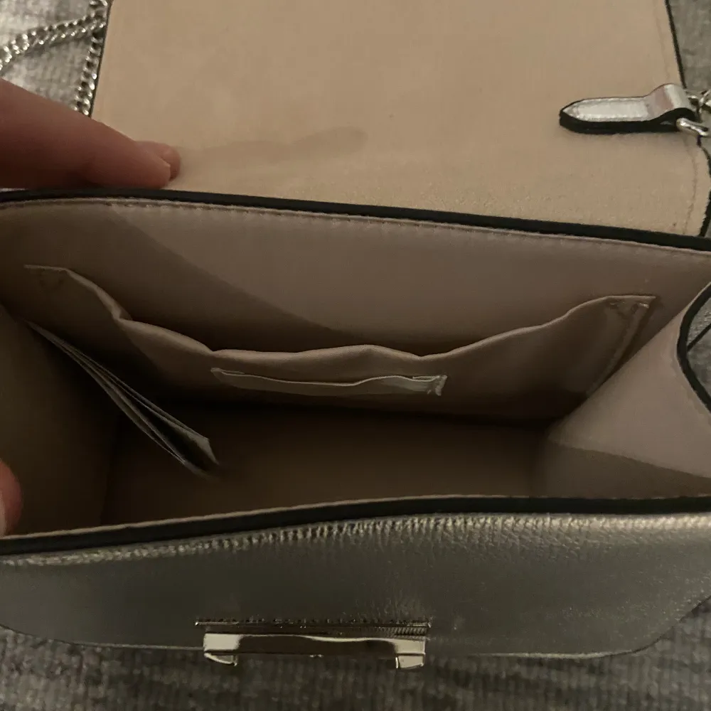 Silvrig väska från h&m. Original pris: 🤷🏼‍♀️ En repa på spegel delen, resterande bra skick.. Väskor.