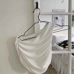 Säljer ett vitt linne som sitter på ena axeln, i ett löst fint material. Storlek XS 