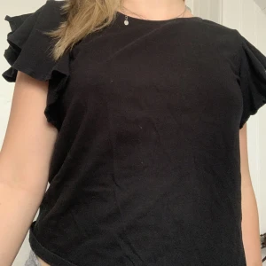 Svart t-shirt - Det ät en svart T-shirt som aldrig används, med volanger på axlarna. Jätte gullig🩷