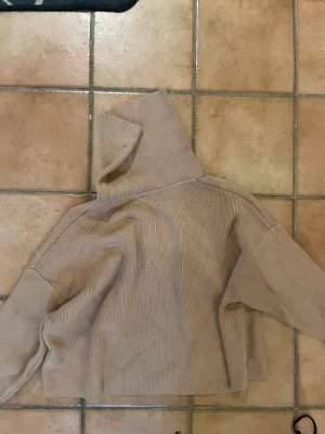 Tjocktröja - Beige stickad tröja med knappt på armarna, turtleneck, väldigt skön.