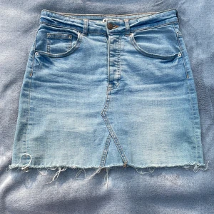 Jeanskjol - En blå jeanskjol med fransar nedtill. Är i gott skick 