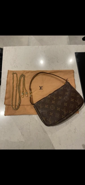 louis vuitton väska - En louis vuitton pochette väska som är i hyfsat bra skick. Man får med långt band och dustbag, även en prislapp från Vestiaire Collective. Serie nummer ser ni på bilden. Lite slitningar på bandet men annars bra skick.