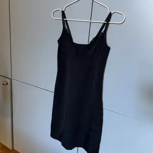 Kort svart klänning i typ underkläder-material. Den är v-ringad med lite spets❣️