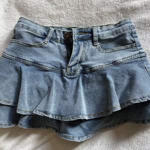 Kort jeanskjol med volanger i storlek S men passar även som XS. Finns inbyggda shorts som gör att man inte flashar nåt!🙌Har aldrig använts och är i god skick! Däremot sitter byxknappeb lite löst.