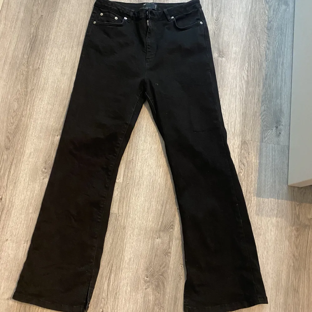 Svarta jeans från asos i storlek 32/28 petite . Jeansen har slits längst ner på bena och är använd ett fåtal gånger. . Jeans & Byxor.