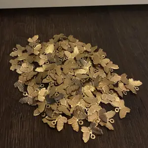 100 st guldiga fjärilsberlocker till salu.