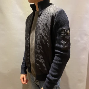 J. Lindeberg  - Säljer nu min J. Lindeberg cardigan. Beck knitted hybrid jacket, strl M. Jackan är i ett otroligt bra skick! Sparsamt använd. Personen på bilden är 1,81cm och vikt 75kg. Köparen står för frakten. Nypris: 3195kr. är beredd att diskutera om priset!
