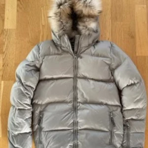 Dunjacka Ver de Terre 14-16 år, fint skick - Beige dunjacka från kvalitetsmärket Ver de Terre, storlek 16 år men liten i storleken. Avtagbar luva med päls, snölås nertill. Mycket fint skick. Nypris: ca 3000kr