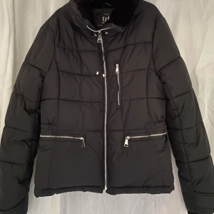 Jacka från Zara  - En jättefin jacka från kollektionen ”trf - Zara” som är så gott som ny. Har en krage med fusk päls och tre fickor samt fina detaljer på ärmarna. Den är lite croppad och påminner om en pufferjacket. Finns en luva till med! 