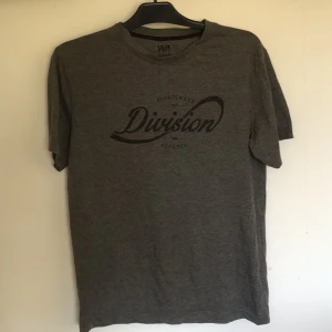 Grå T shirt med tryck i stl S - Detta är en grå T Shirt Med tryck i form av text. Den är i fint skick. 