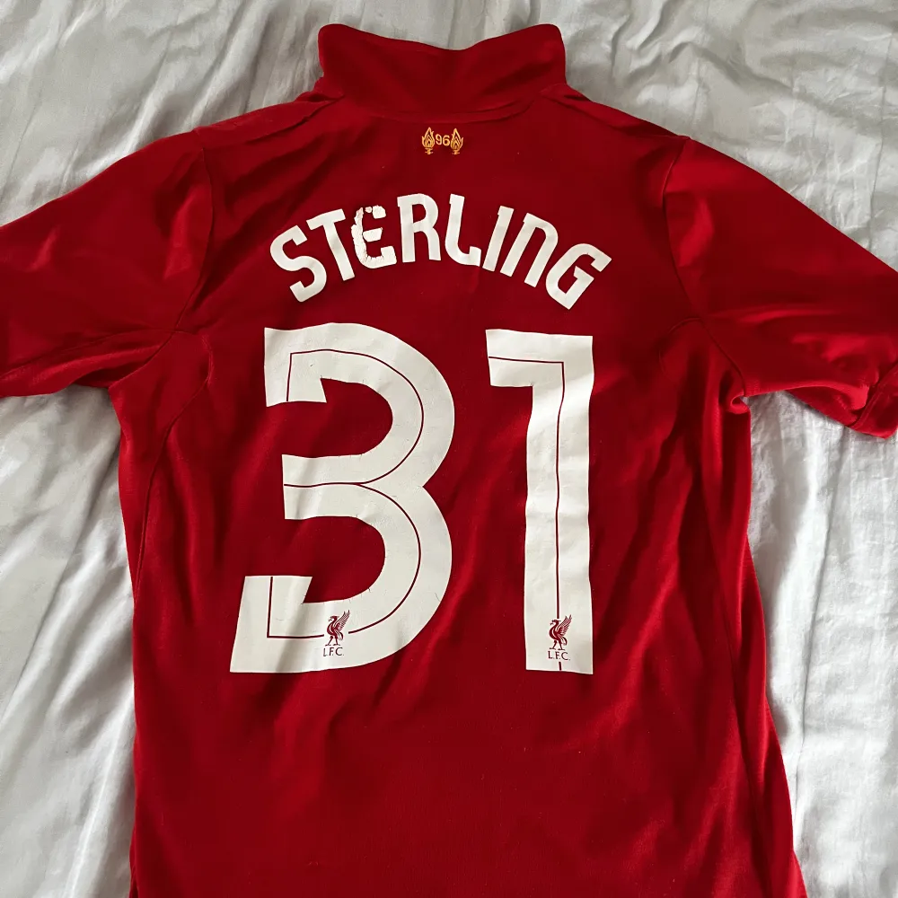 Liverpool tröja i strl 158 Raheem sterling. Ovanlig tröja! Bra skick men en liten defekt på en bokstav bak (se bild). Skönt material!  . T-shirts.